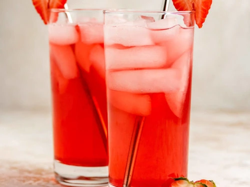 Two glasses of strawberry soda with metal straws.