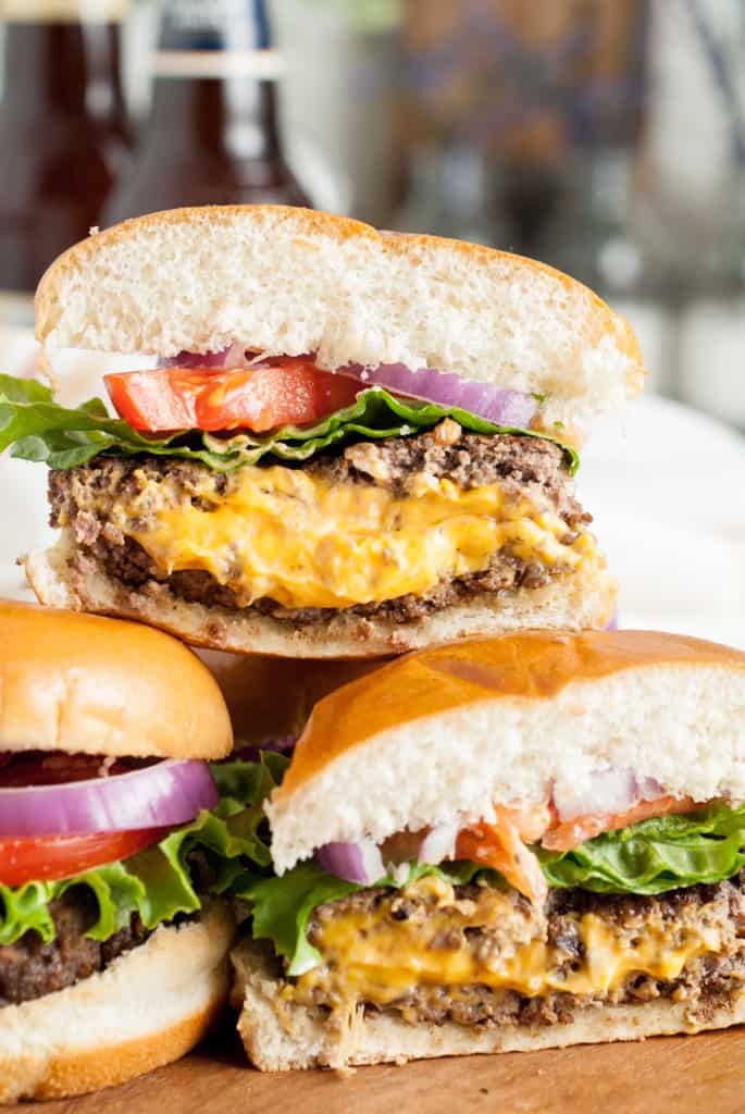 Close up of three juicy lucy burgers on a cutting board.