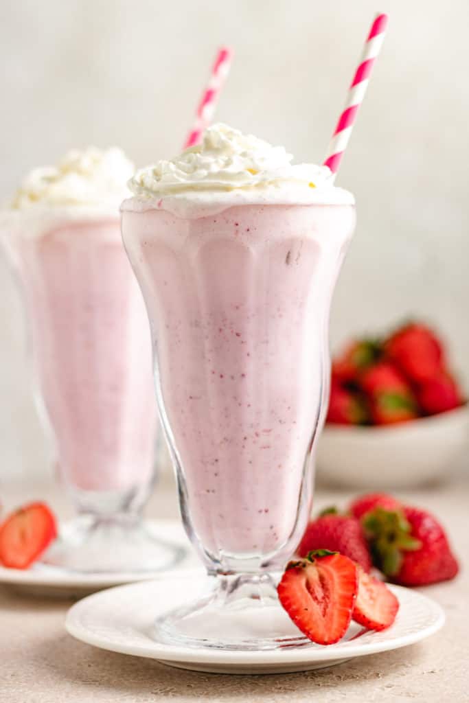 Side view of strawberry shakes with straws.