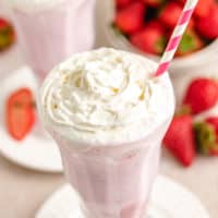 Tall glass filled with a strawberry shake.