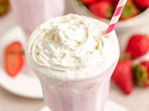 Tall glass filled with a strawberry shake.