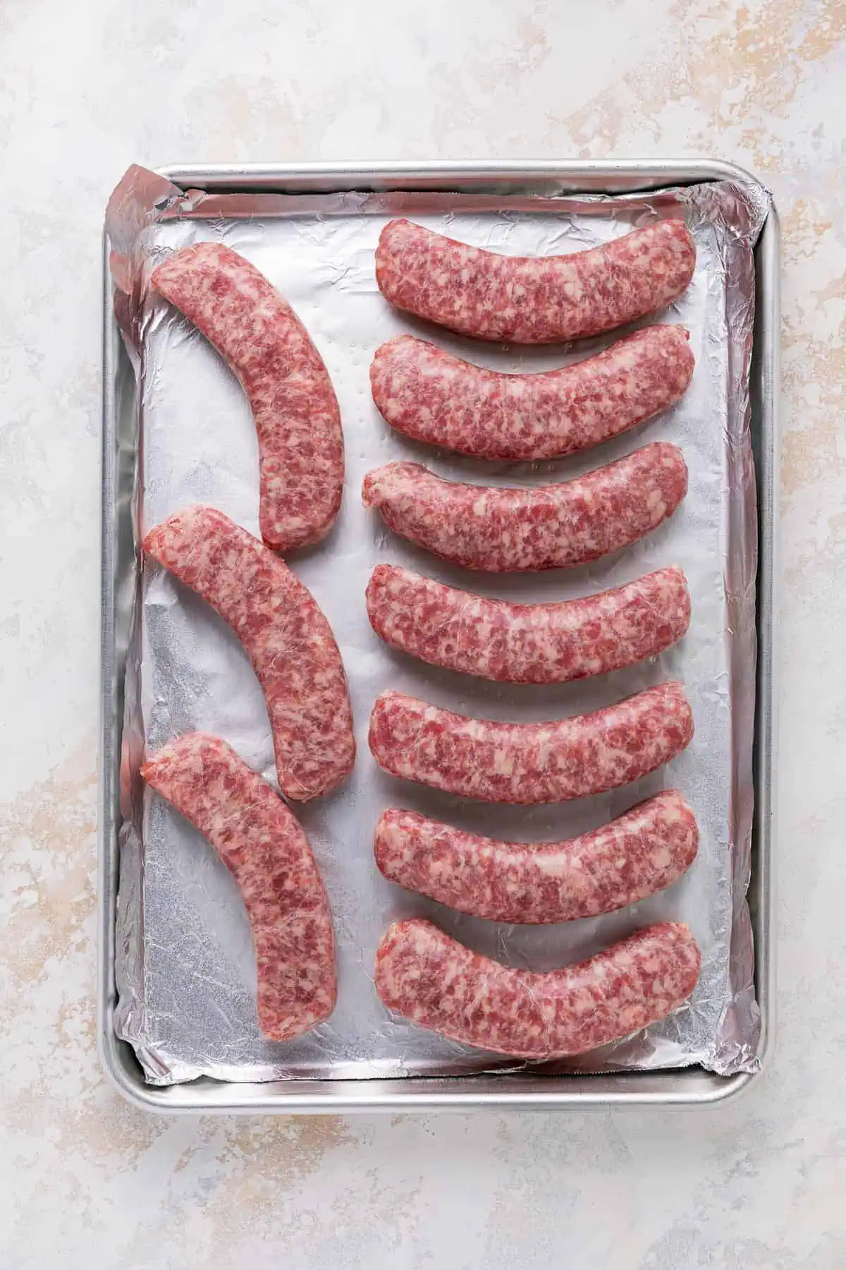 Unbaked brats on a pan.