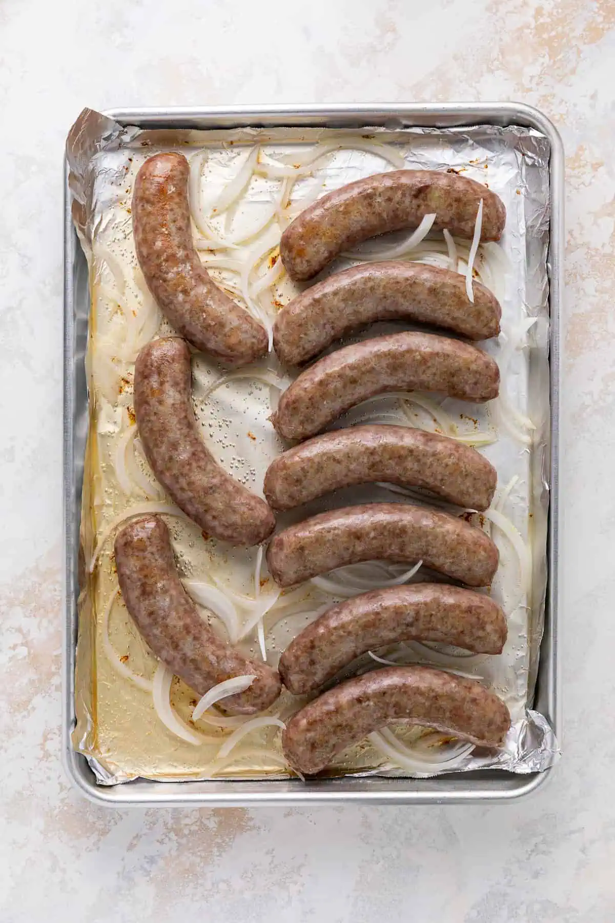 Onions and brats on a sheet pan.