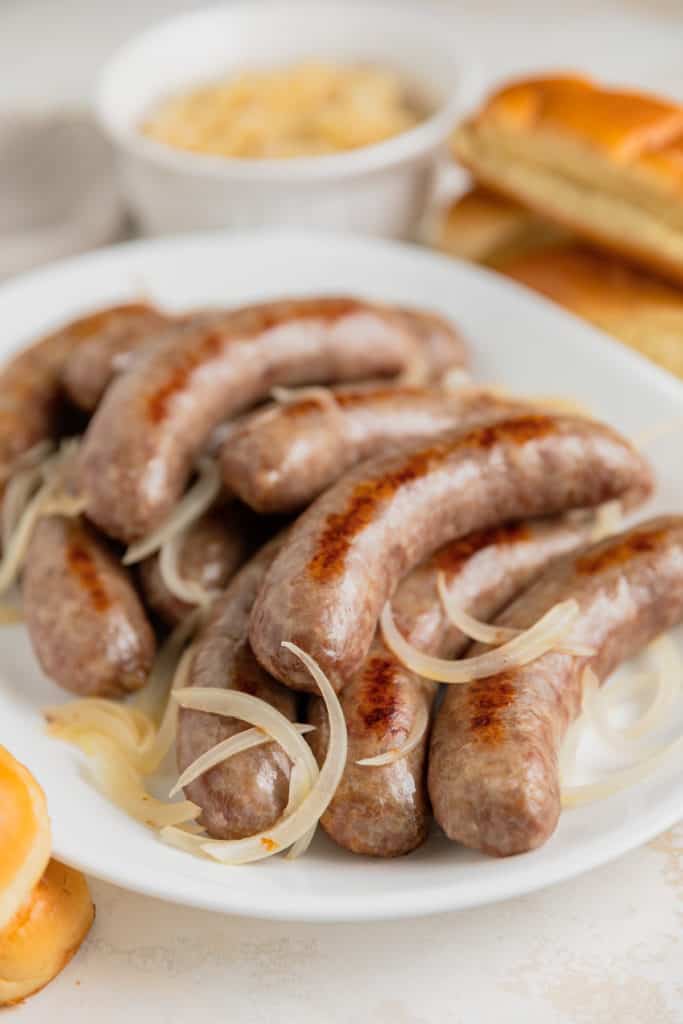 Baked brats and onions on a plate.