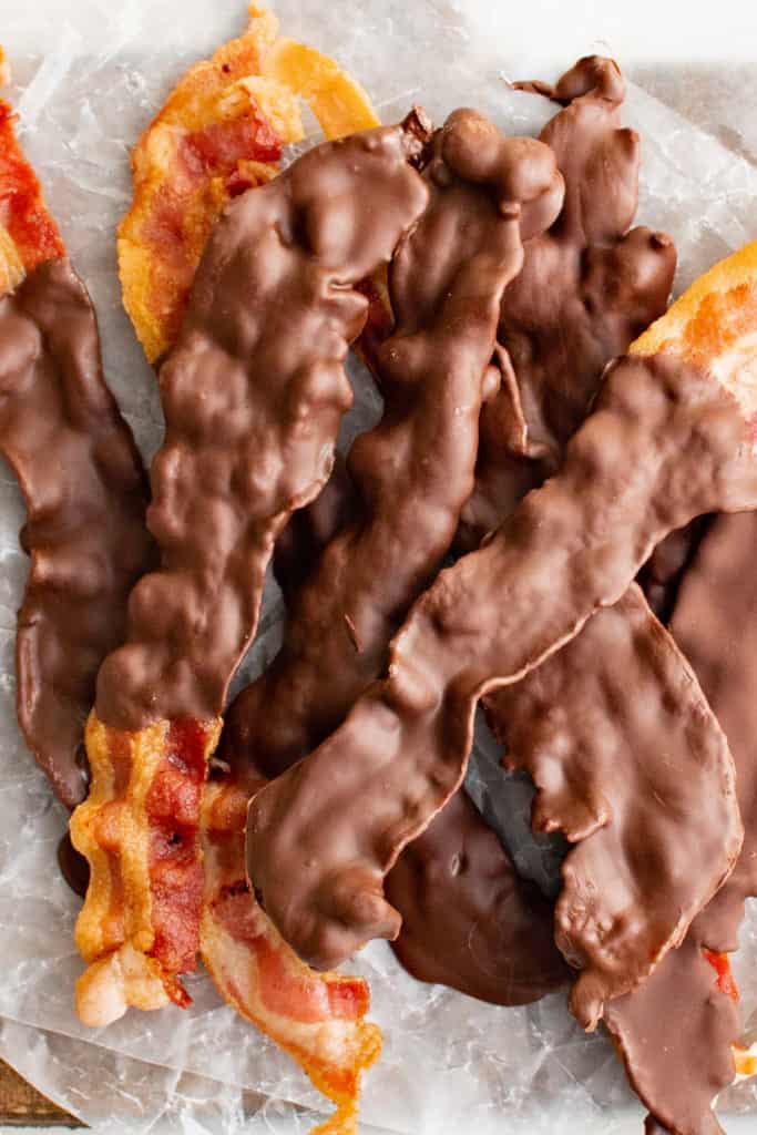 Batch of chocolate covered bacon on parchment.