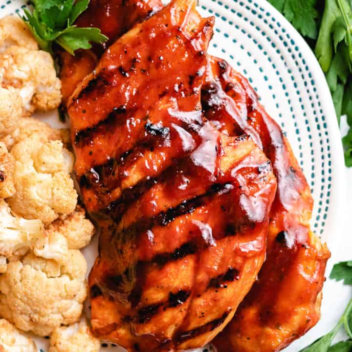 Top down view of grilled bbq chicken breasts on a plate.