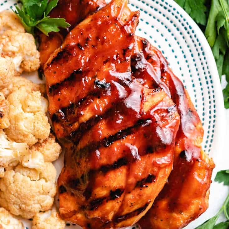Top down view of grilled BBQ chicken breasts on a plate.