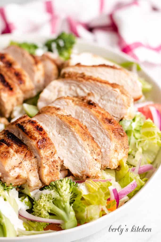 Grilled and sliced chicken served over a salad.