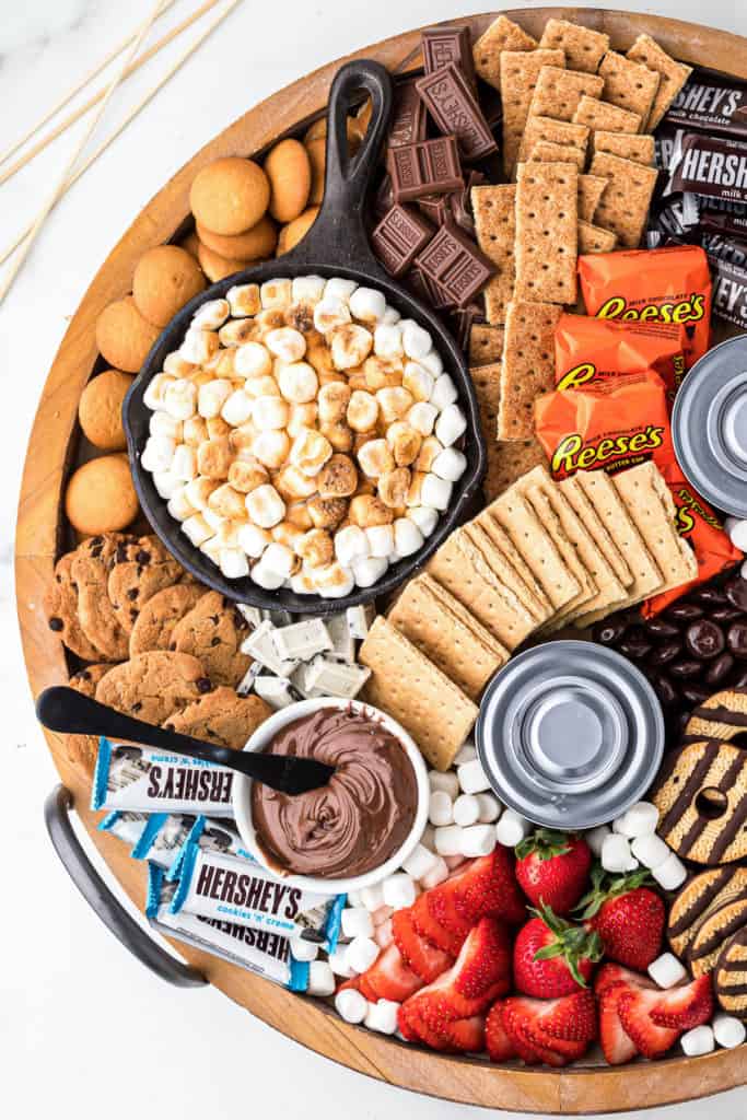 Marshmallow dip, crackers and candy on a wooden board.