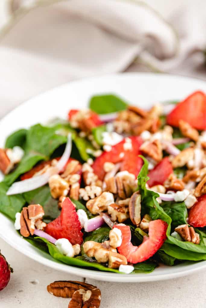 Side view of a strawberry goat cheese salad with pecans.