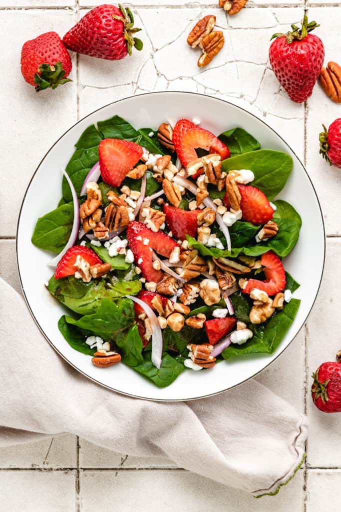 Close up view of a strawberry goat cheese salad with pecans.