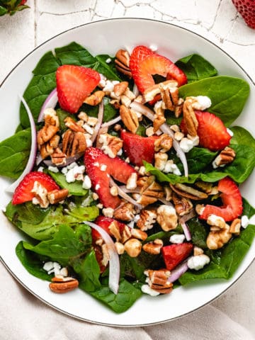 Top down view of strawberry spinach salad with goat cheese.