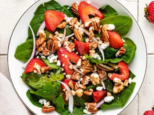 Top down view of strawberry spinach salad with goat cheese.