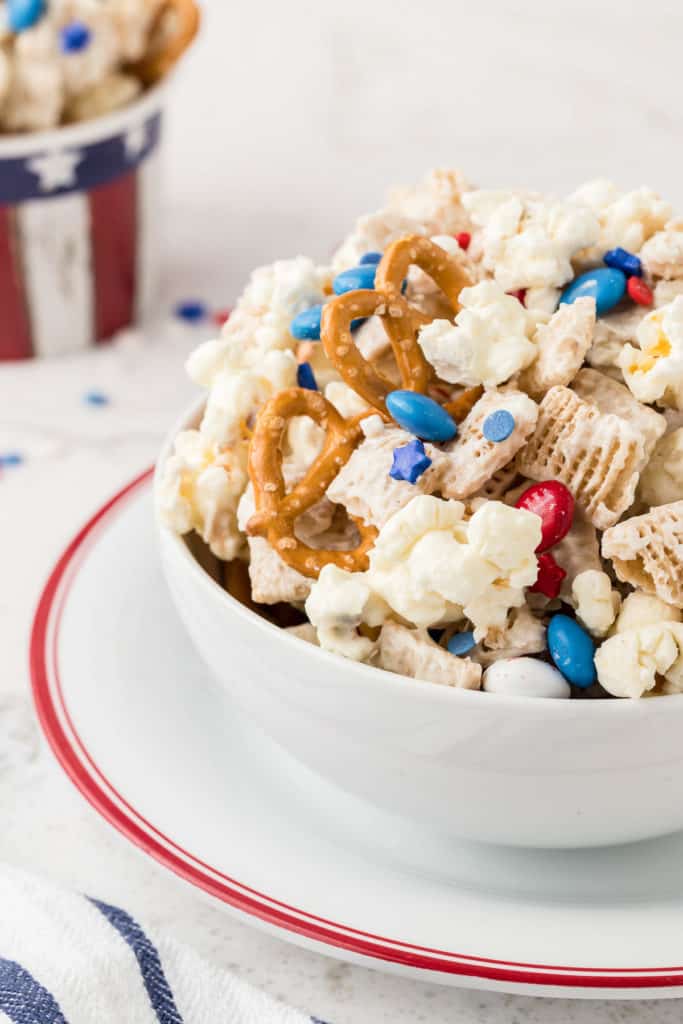 White bowl filled with red, white and blue snack mix.
