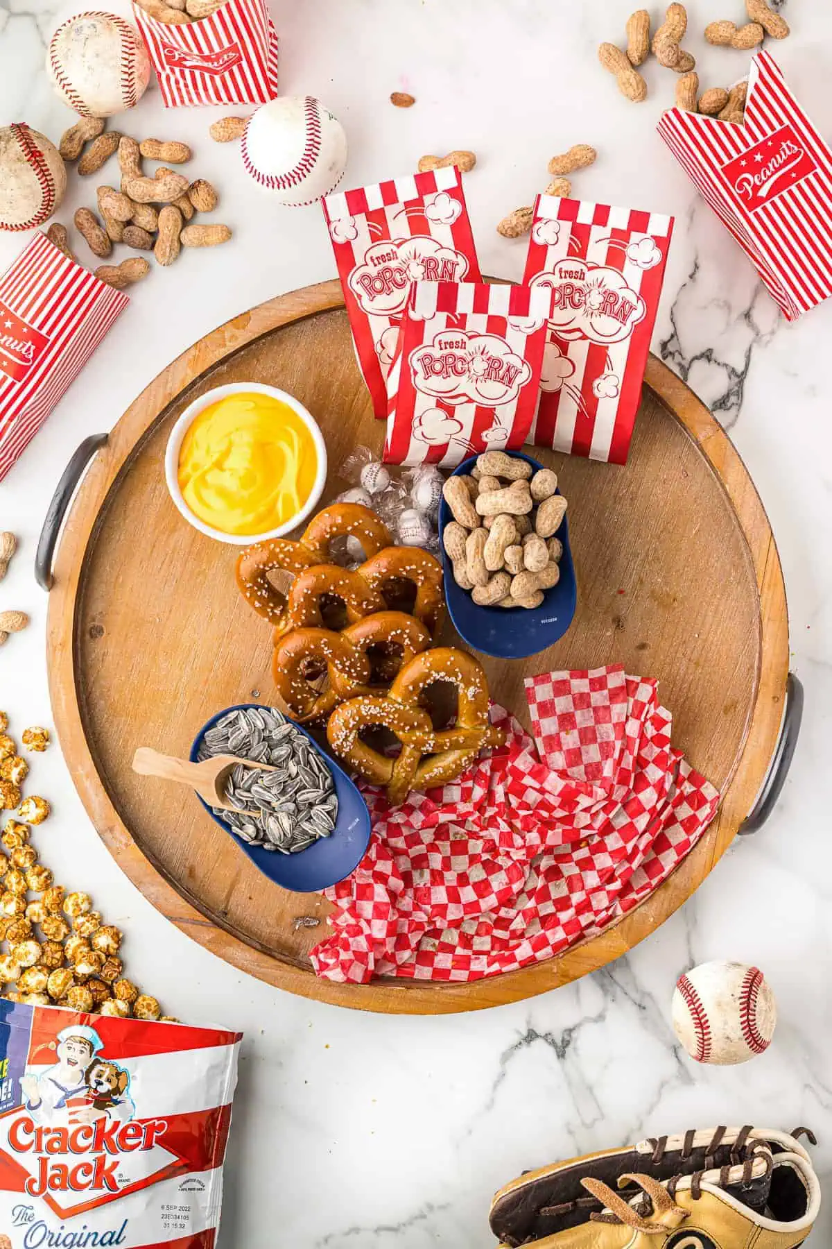 Pretzels, cheese, and candy popcorn, peanuts and sunflower seeds on a board.