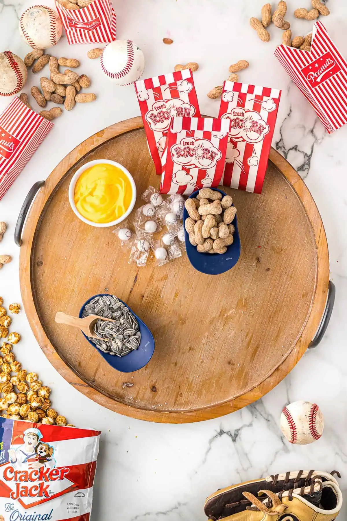 Nacho cheese, popcorn, peanuts and sunflower seeds on a board.