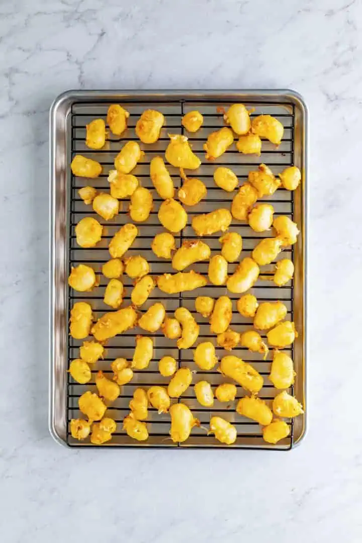 Cheese curds drying on a sheet tray.
