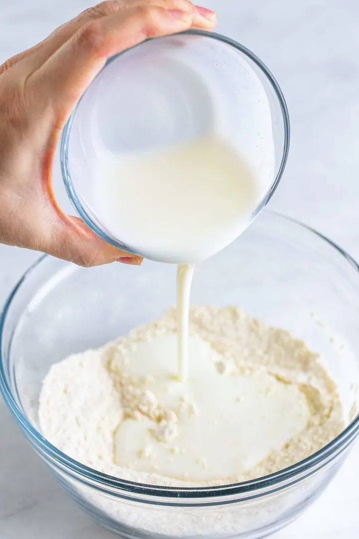 Buttermilk being poured into seasoned flour.