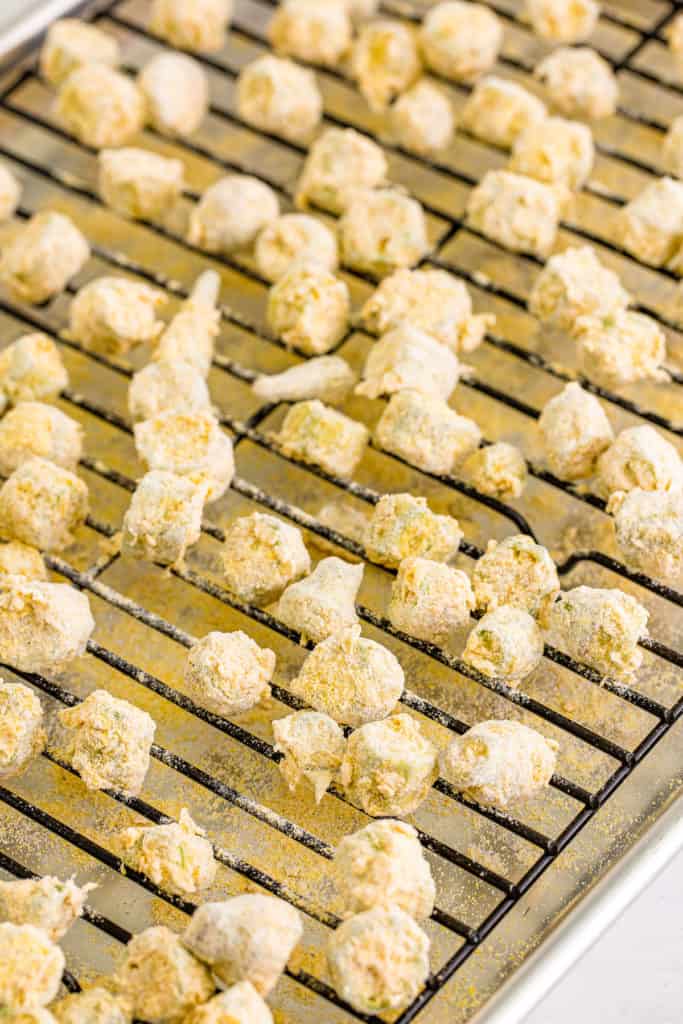 Cornmeal dipped okra on a sheet tray.