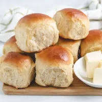 Stack of hawaiian rolls on a cutting board.