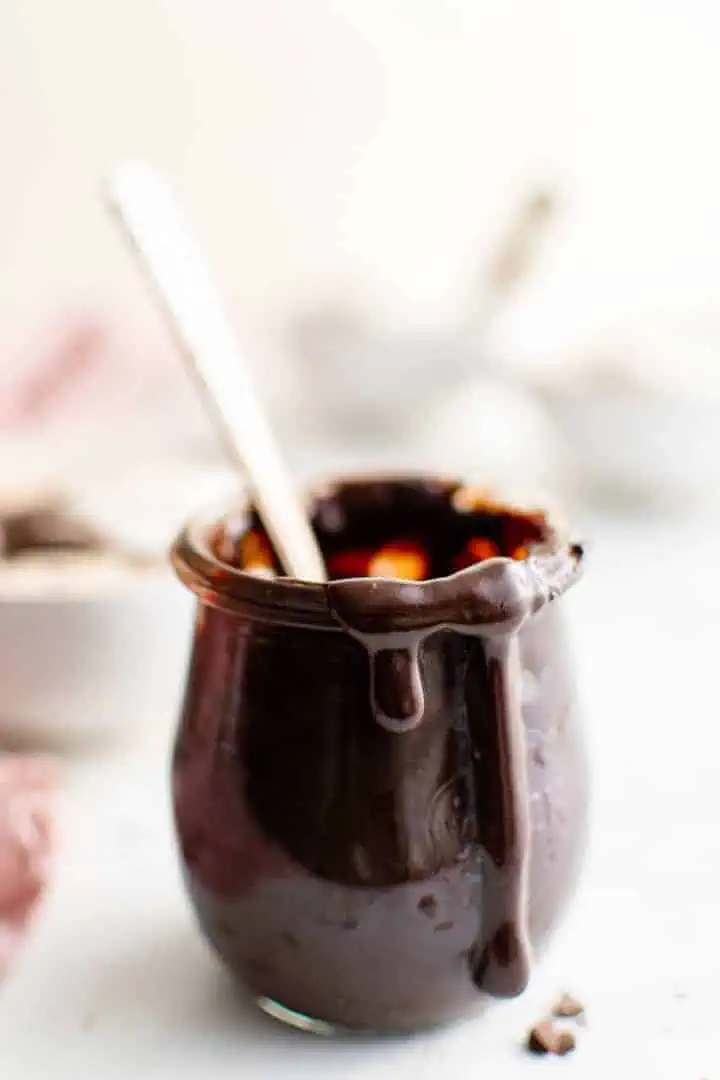 Jar of chocolate sauce with a spoon.