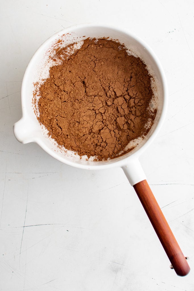 Cocoa powder added to a pan of sweetened milk.