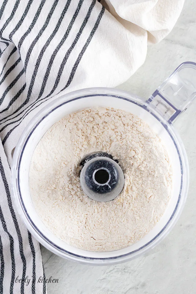 Top-down view of a food processor with the mixed dry ingredients.
