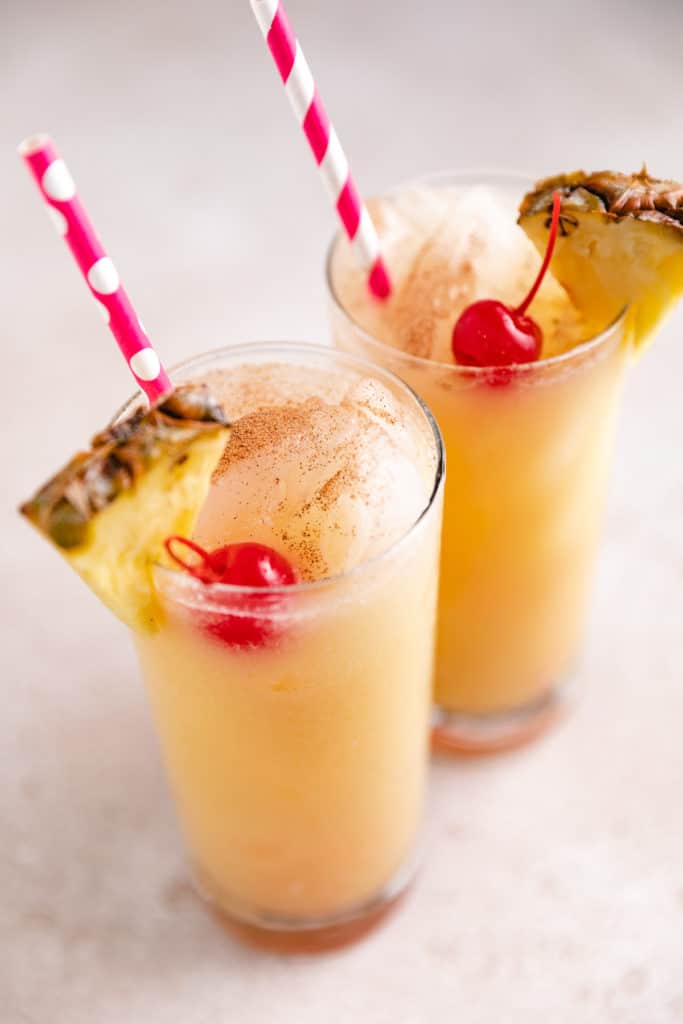Two pineapple drinks with a sprinkle of nutmeg.