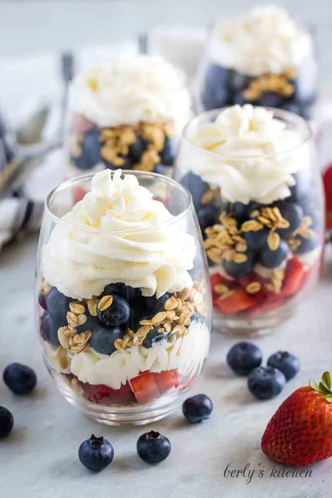 Several strawberry blueberry granola parfaits in cups.