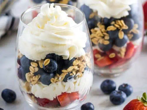 Whipped cream and granola layered in a fruit parfait.