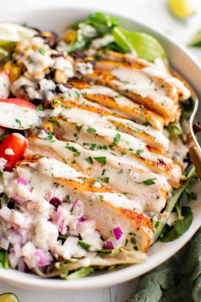 Close up view of spicy ranch dressing drizzled over chicken salad.