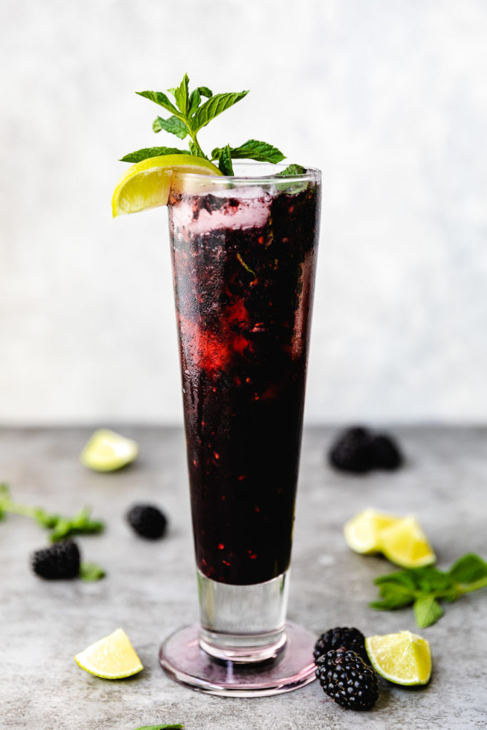 Tall glass filled with berry mojito.