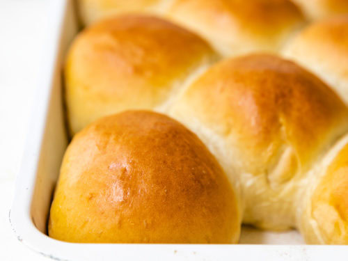 Freshly baked rolls in a white pan.