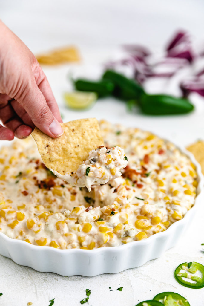 Chip dipping into corn dip.