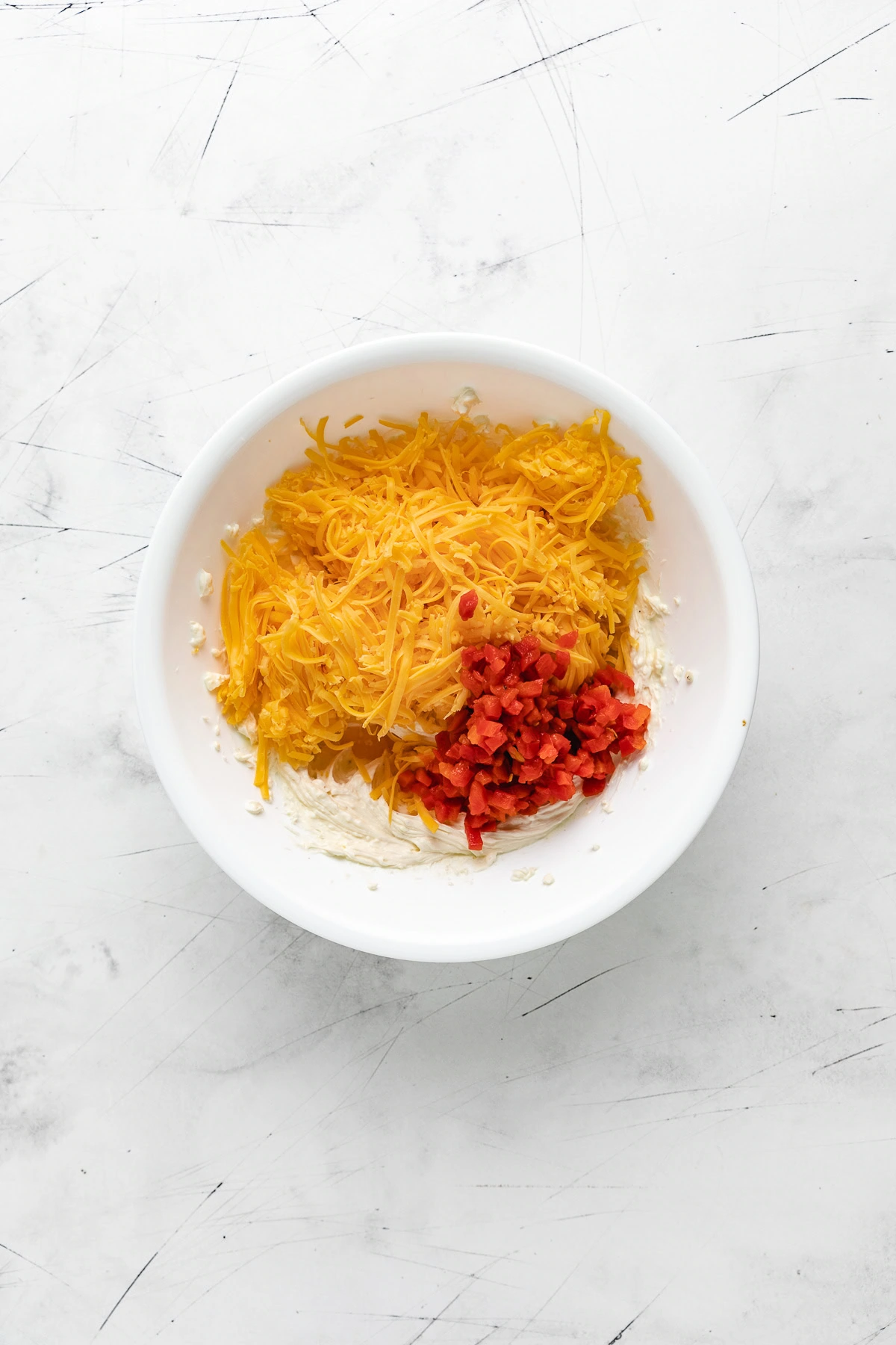 Shredded cheddar cheese and pimentos in a bowl.