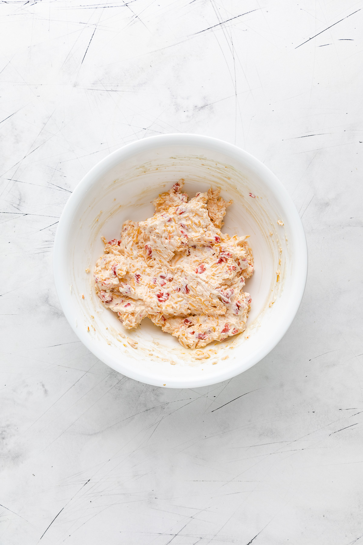 White mixing bowl filled with pimento cheese dip.