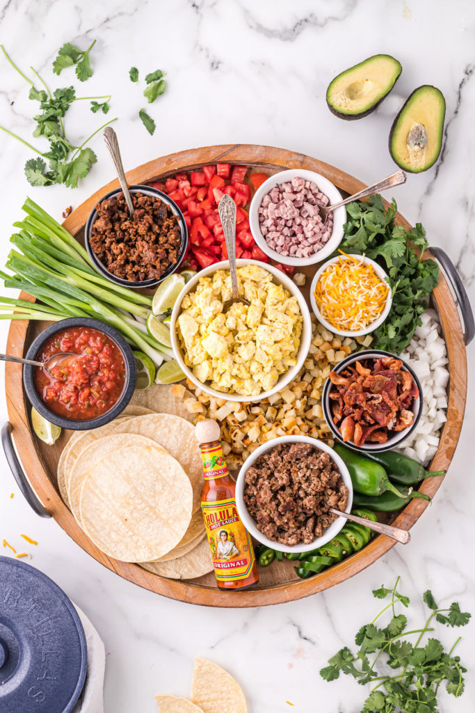 Foods used to make breakfast tacos on a wooden board.