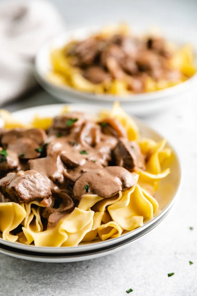 Side view of mushrooms and beef on noodles.