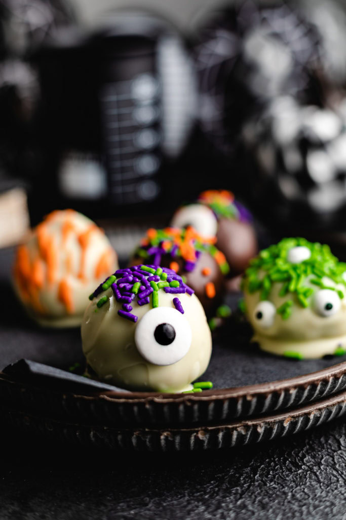 Decorated holiday truffles on plates.