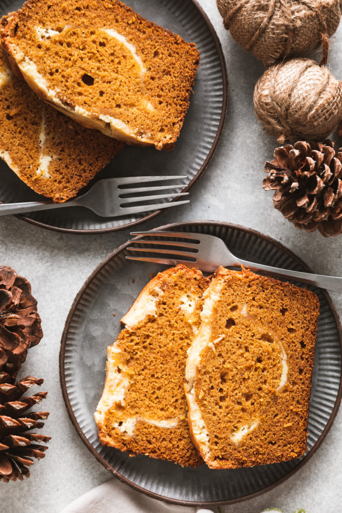 Two pieces of pumpkin bread with cream cheese.