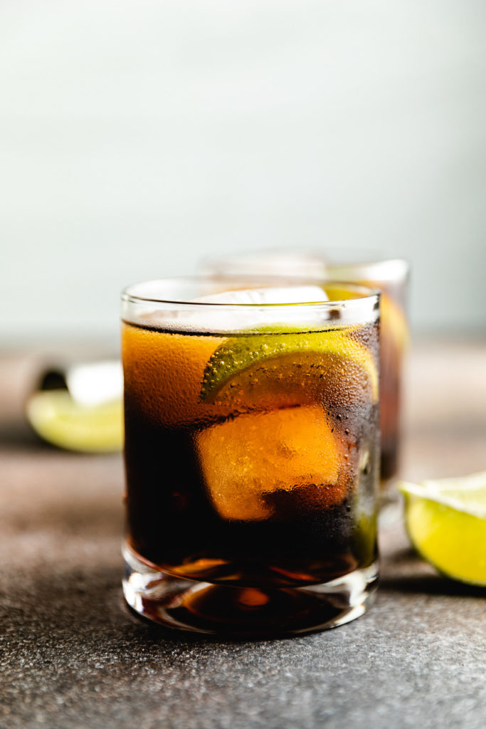 Coke and rum with a lime in a glass.