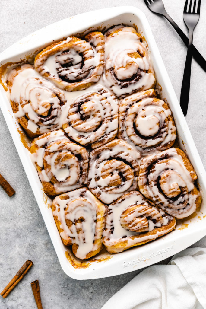 Sweet vanilla icing drizzled over cinnamon buns.
