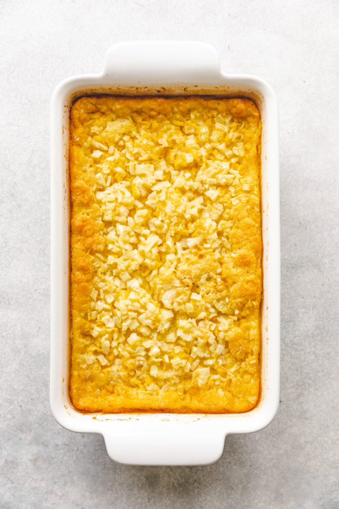 Corn casserole with onions in a baking dish.