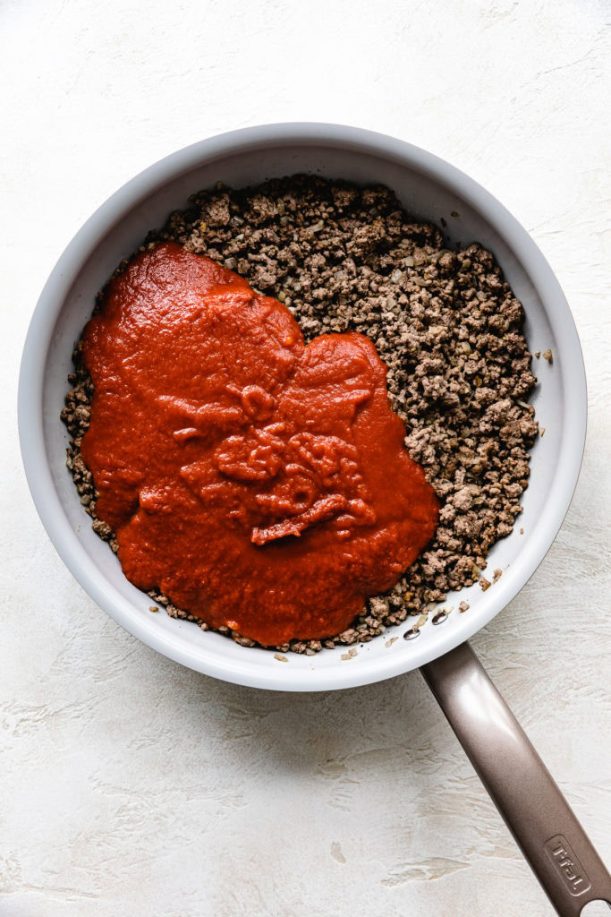 Marinara poured over seasoned ground beef.