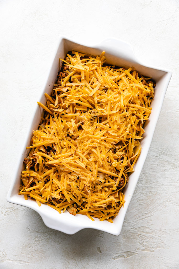 Shredded cheese added to the top of a ground beef casserole.