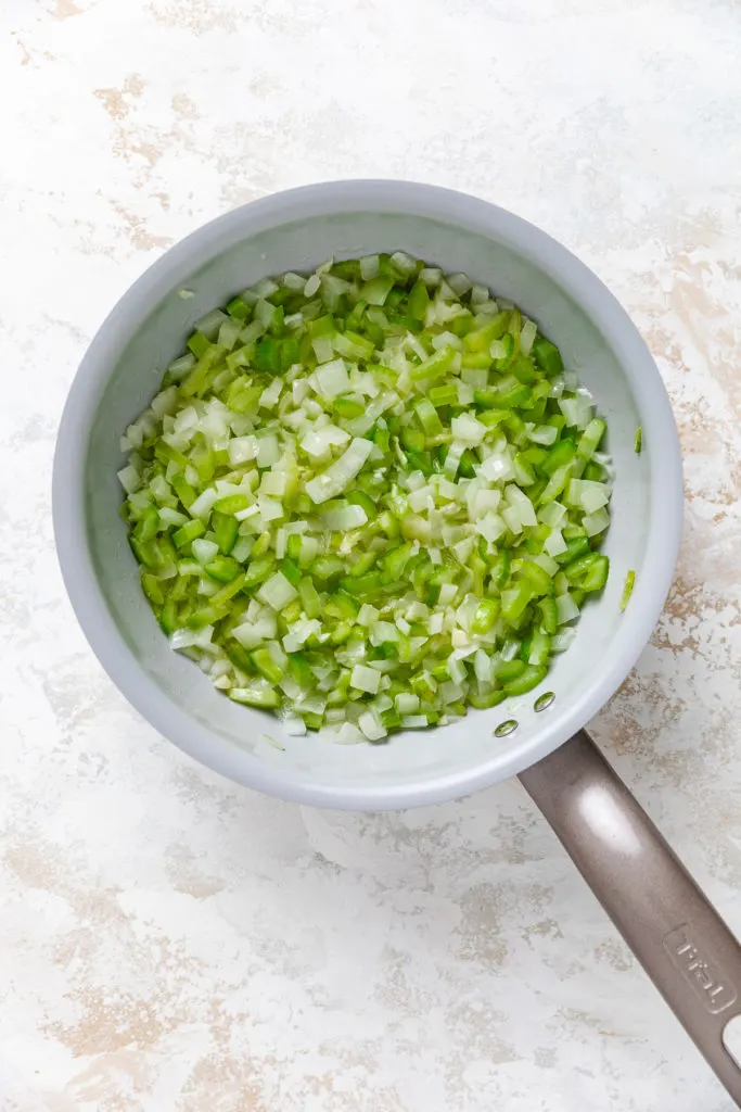 Sauteed onions and celery in a pan.