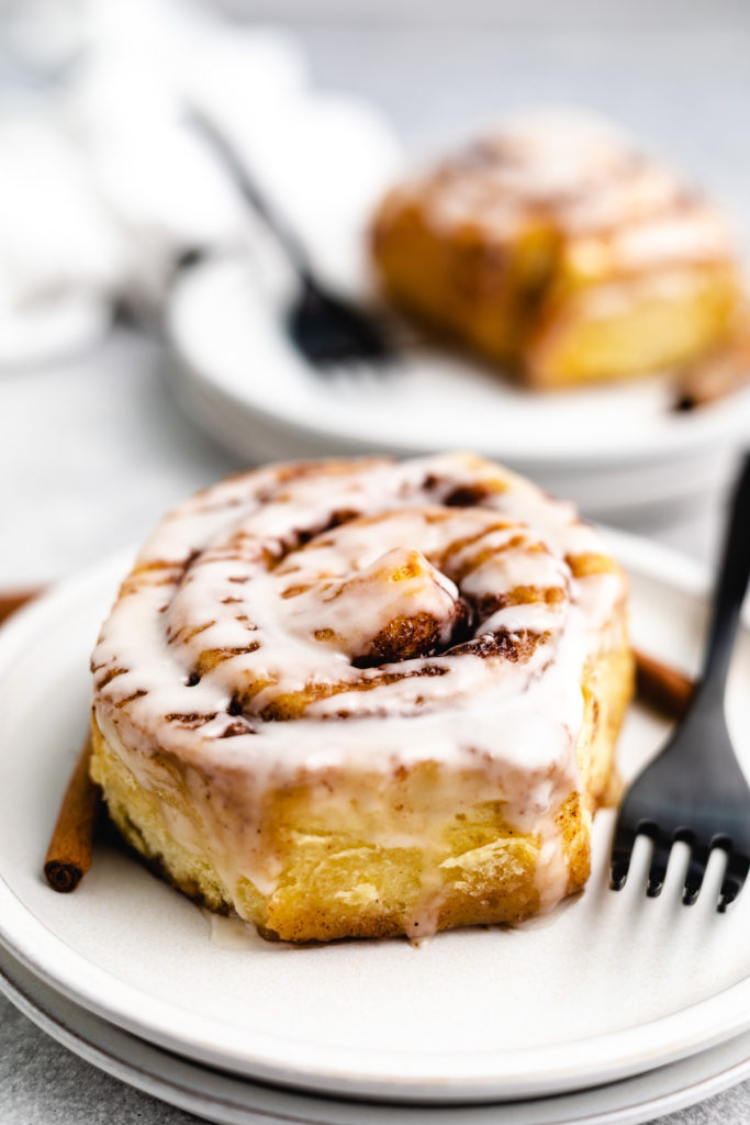 Sweet rolls on a plate with cinnamon sticks.