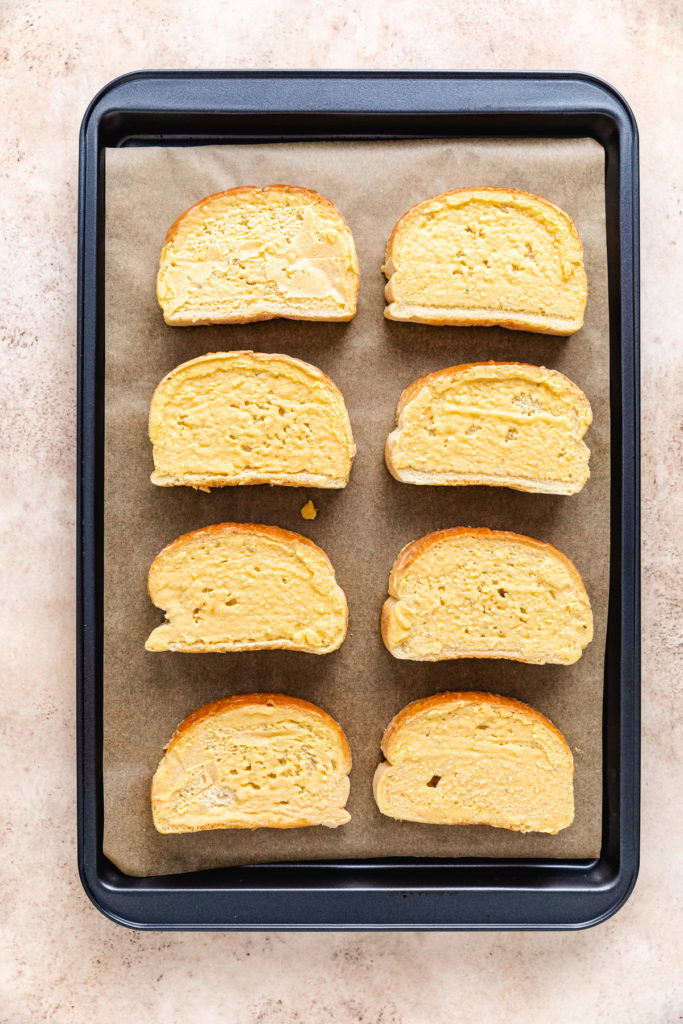 Frozen garlic bread on a sheet pan.