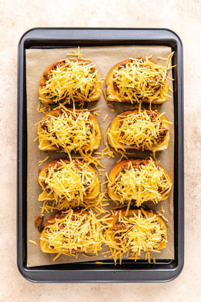 Shredded cheese on top on open faced sloppy joes.