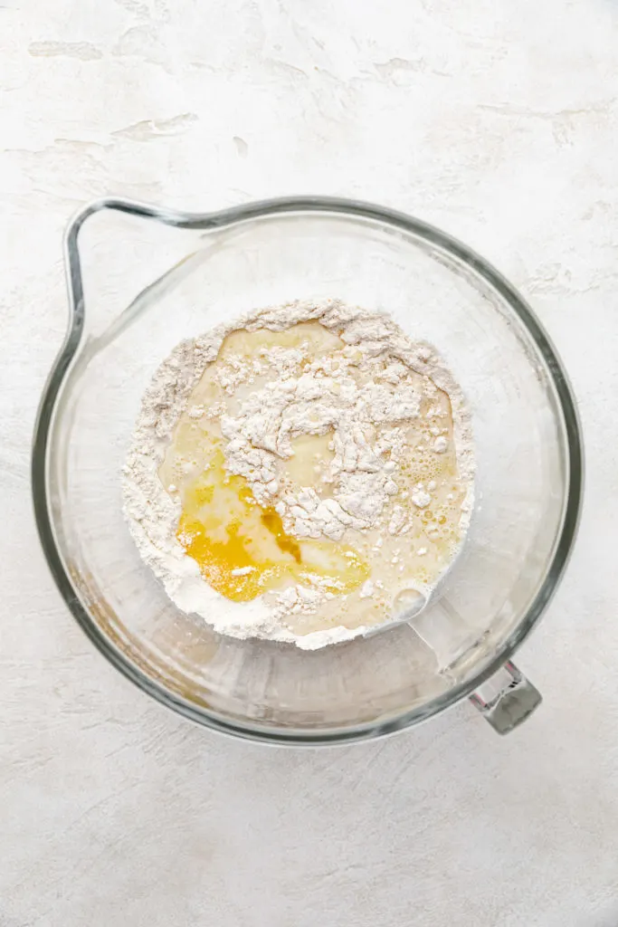 Flour, yeast, eggs, melted butter and other ingredients in a bowl.